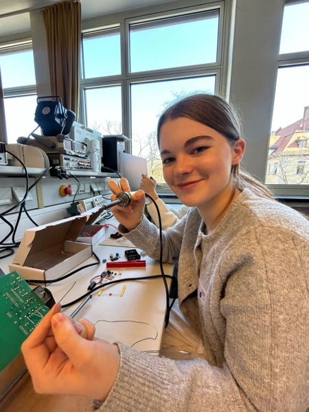 Mädchen mit Lötkolben und Elektronikteilen