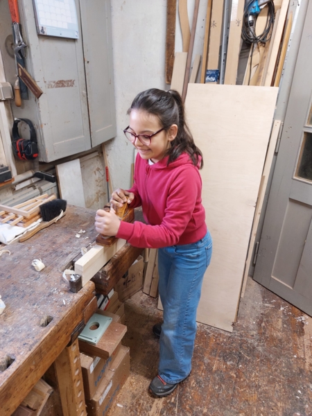 Mädchen mit Hobel an Werkbank