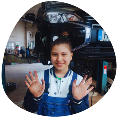 Mädchen mit schmutzigen Händen vor einer Auto-Hebebühne