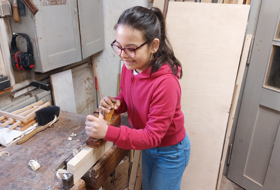Mädchen mit Hobel an Werkbank