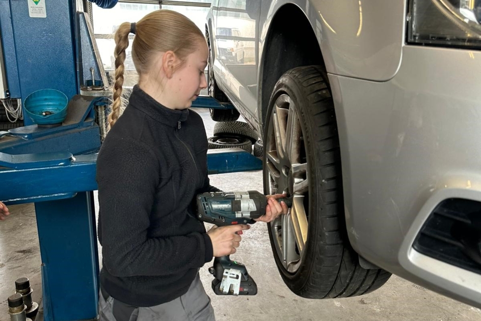 Mädchen schraubt einen Autoreifen fest.