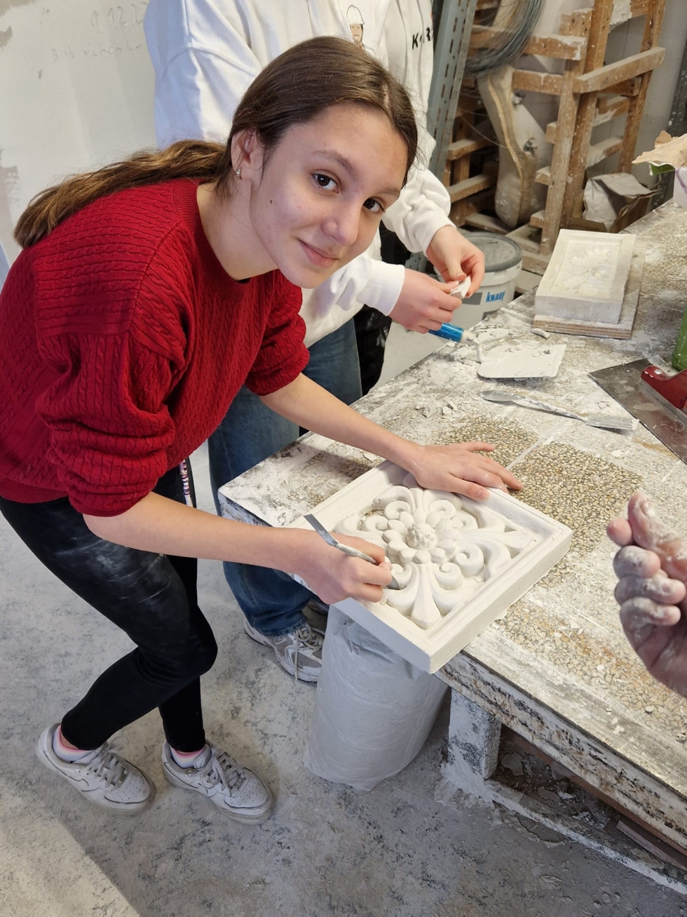 Mädchen arbeitet an einer Stuckrosette.