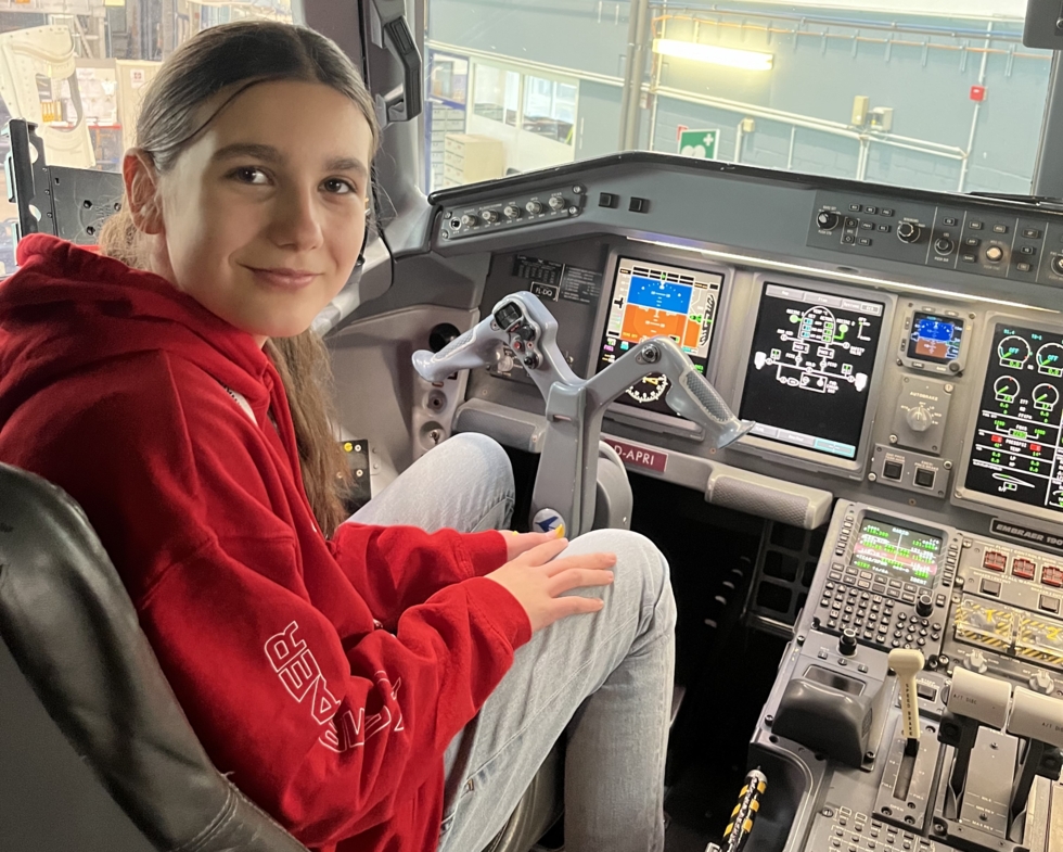 Mädchen sitzt am Steuer im Cockpit eines Flugzeugs.