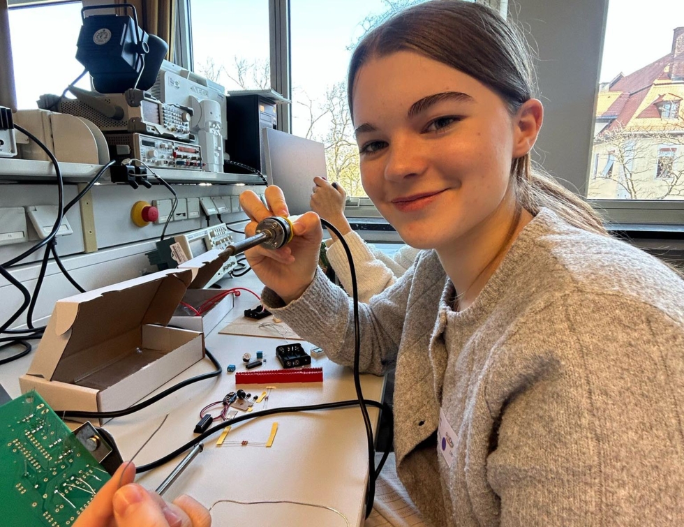 Mädchen mit Lötkolben und Elektronikteilen