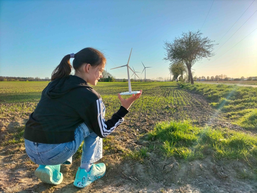 Mädchen mit Windradmodell vor Windrädern