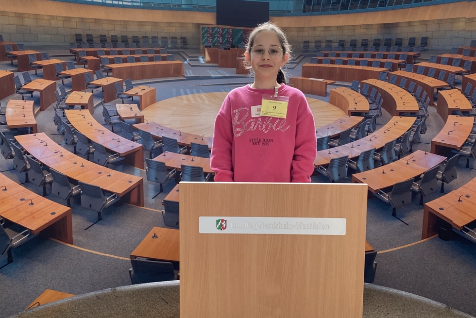 Mädchen steht an einem Redenpult im Plenarsaal des Landtags NRW.